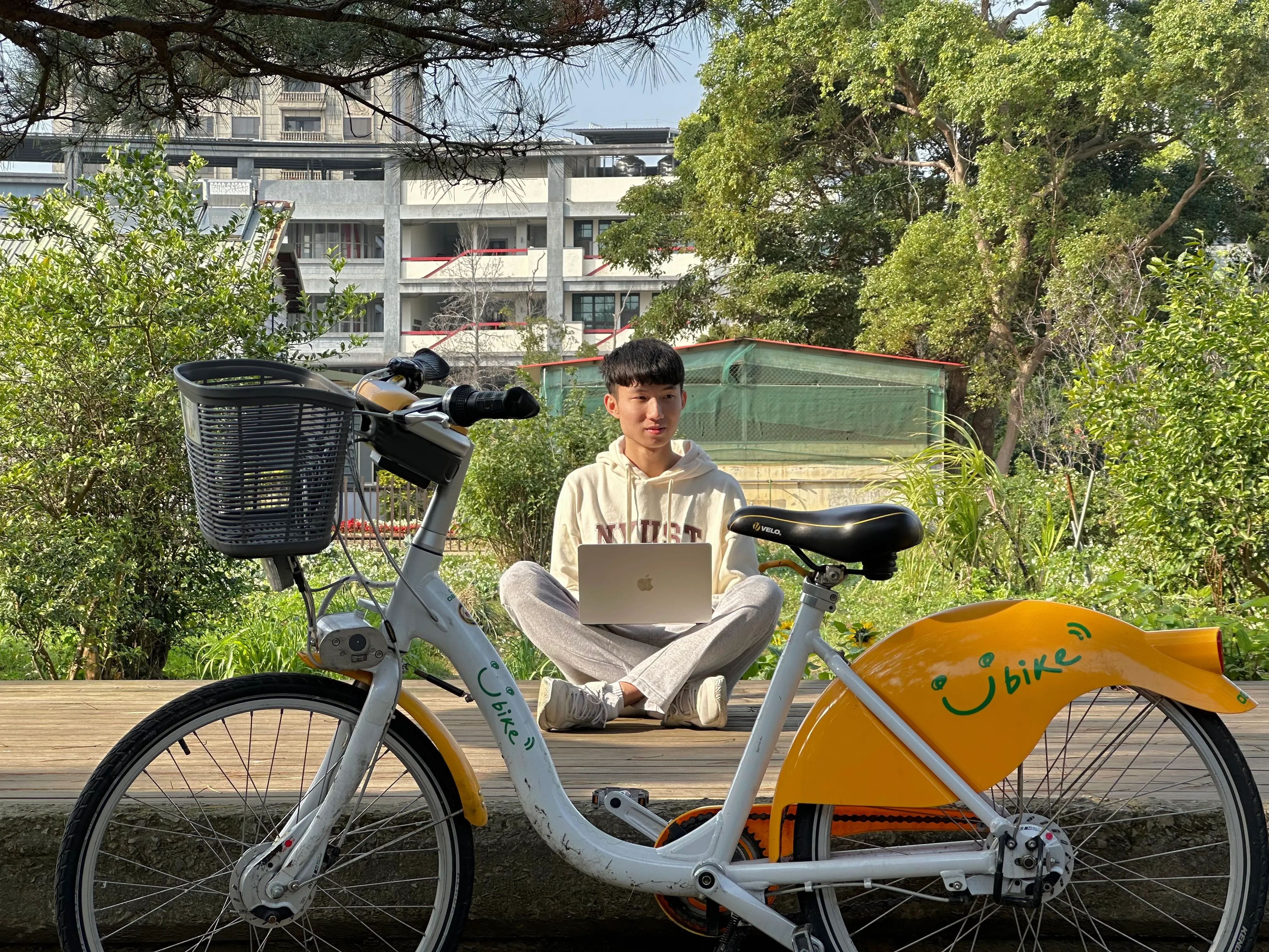江祐鈞在 Ubike 後面盤腿坐著用筆電